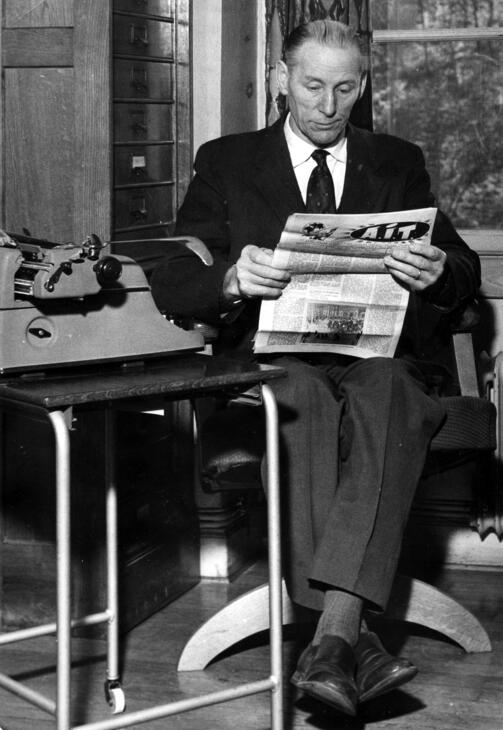Tidningen Arbetarens chefredaktör Evert Arvidsson läser tidningen A.I.T. vid sin skrivmaskin på redaktionen på Sveavägen 98, vid mitten av 1950-talet.