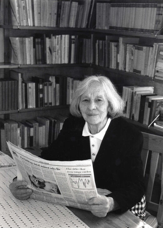 Författaren och översättaren Britta Gröndahl i sitt hem, sittande vid ett bord framför en bokhylla, maj 1994.
